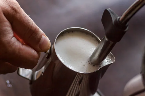 Professional bartender warming milk for cappuccino. Barista usin