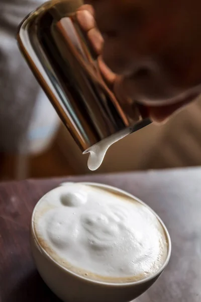 Uomo versando in una tazza di caffè con latte — Foto Stock