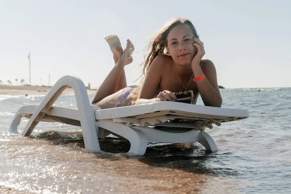 Young woman in chaise lounge at the sea beach. Girl relax on bea — Stock Photo, Image