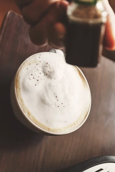 La mano espolvorea especias de café-capuchino, canela, chocolate —  Fotos de Stock