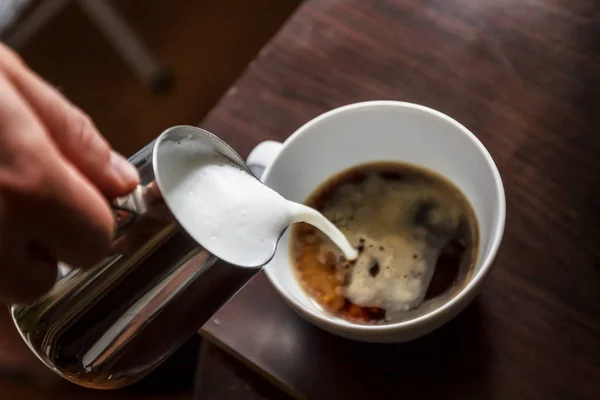 Homem derramando em uma xícara de café com leite — Fotografia de Stock
