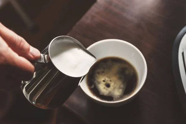 Hombre vertiendo en una taza de café con leche — Foto de Stock