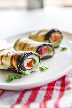 hafif bir arka plan üzerinde beyaz bir tabak üzerinde kızarmış patlıcan, süzme peynir ve domates geleneksel çanak üç rulo. Minimalizm. Yukarıdan görüntüle