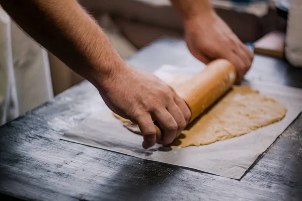 Baker's hands roll ginger dough on a dark background. Close-up, soft focus. Side view, top view. Copy space. — Stock Photo, Image