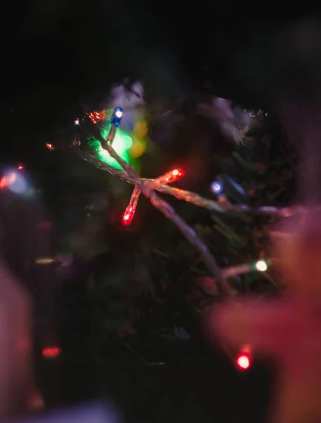 Coloreado con luces una guirnalda en un árbol decorado de Navidad en borroso, bokeh. Primer plano . — Foto de Stock