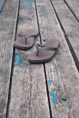Kahverengi parmak arası terlikler eski ahşap güverte demirleme arka planında