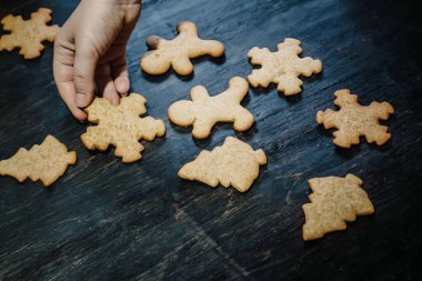 Noel kurabiyelerini koyu ahşap bir masa üzerindeki renkli jölelerle süsleyin.