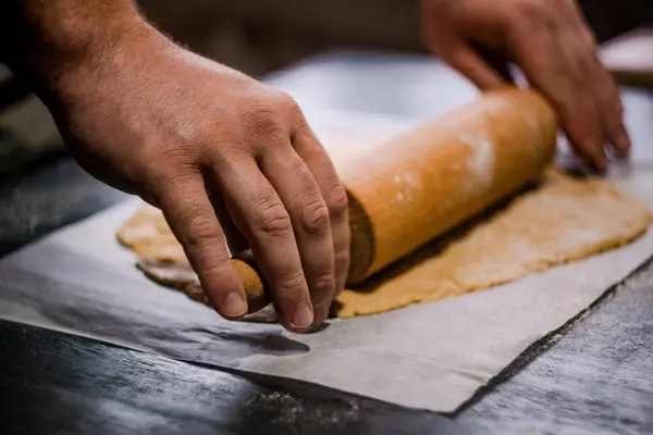 Baker's hands roll ginger dough on a dark background. Close-up, soft focus. Side view, top view. Copy space. — Stock Photo, Image