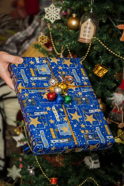 Zapakowane prezenty pod świątecznie zdobione choinki w rękach. Styl życia — Zdjęcie stockowe
