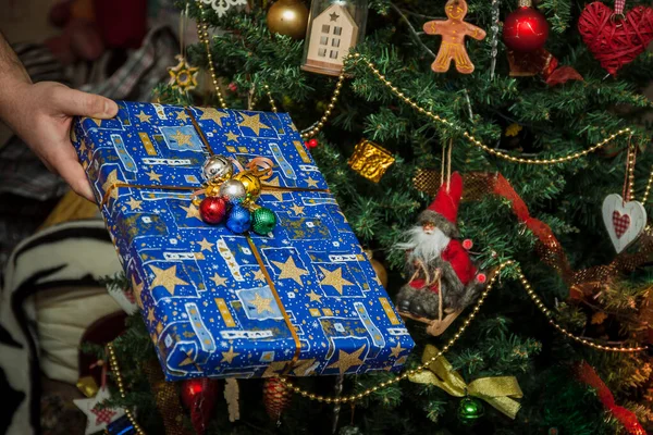 Zapakowane prezenty pod świątecznie zdobione choinki w rękach. Styl życia — Zdjęcie stockowe