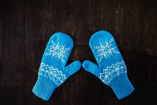 Ein Paar blaue Strickhandschuhe auf dunkelblau-grün-braunem Holz — Stockfoto