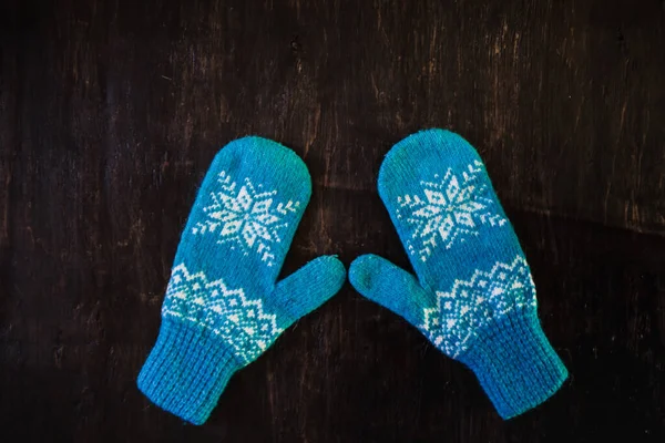 A pair of blue knitted mittens on a dark blue-green-brown wooden — Stock Photo, Image