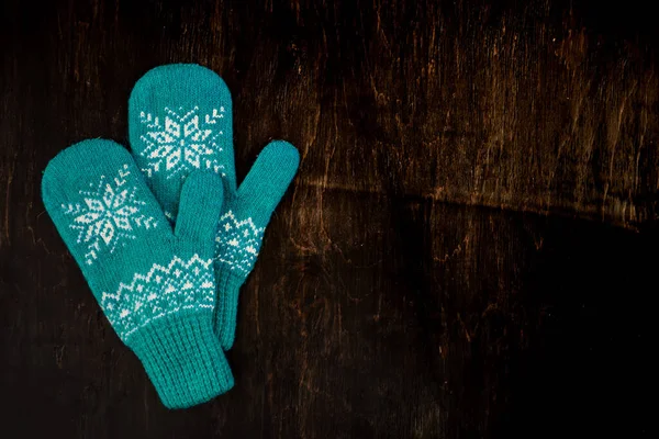 A pair of blue knitted mittens on a dark blue-green-brown wooden — Stock Photo, Image