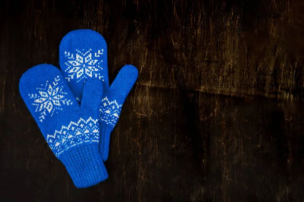 A pair of blue knitted mittens on a dark blue-green-brown wooden — Stock Photo, Image