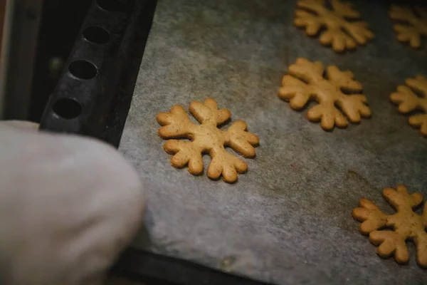 เพื่อให้ได้คุกกี้ขนมปังขิงในรูปของเกล็ดหิมะจากถุงมือเตาอบ . — ภาพถ่ายสต็อก