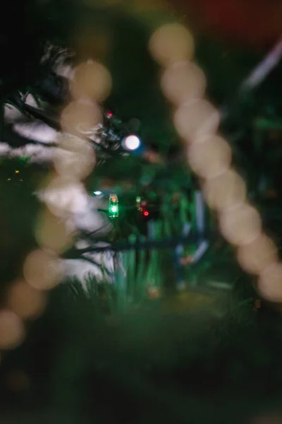 Coloré avec des lumières une guirlande sur un arbre décoré de Noël dans le flou, bokeh. Gros plan . — Photo