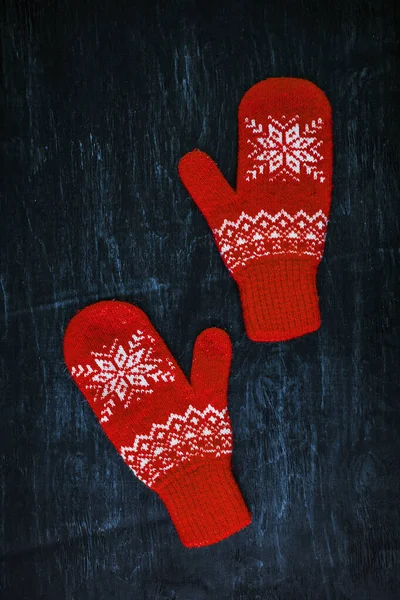 A pair of red-pink-lilac-magenta purple knitted mittens on a dark blue-green-brown wooden — Stock Photo, Image