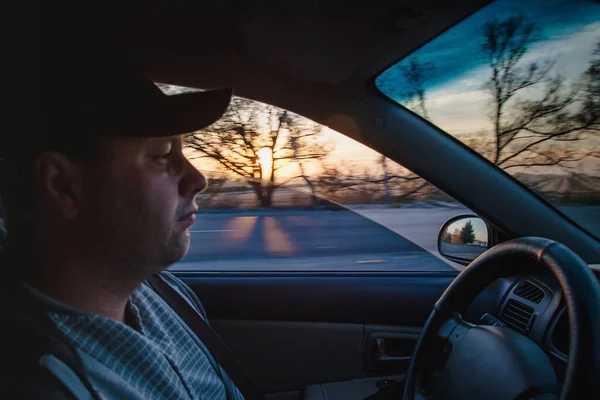 man driving a car at sunset-dawn, close-up, blur. Concept, road trips and travel, freedom of movement