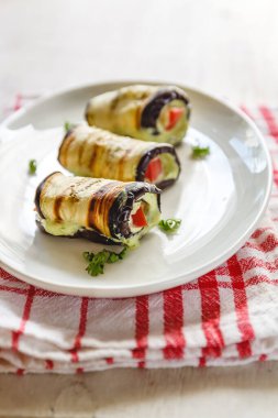 hafif bir arka plan üzerinde beyaz bir tabak üzerinde kızarmış patlıcan, süzme peynir ve domates geleneksel çanak üç rulo. Minimalizm. Yukarıdan görüntüle