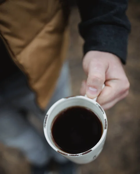 Un hombre sostiene una taza de té con café sobre un fondo de hojas de otoño, vista superior. Ambiente cálido de otoño, enfoque suave . —  Fotos de Stock