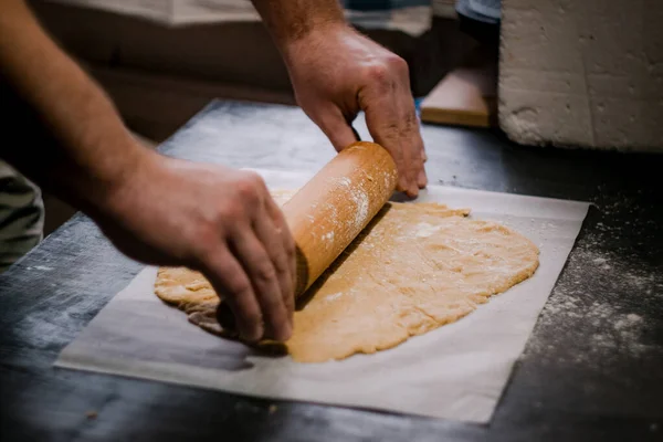 Baker's hands roll ginger dough on a dark background. Close-up, soft focus. Side view, top view. Copy space. — Stock Photo, Image