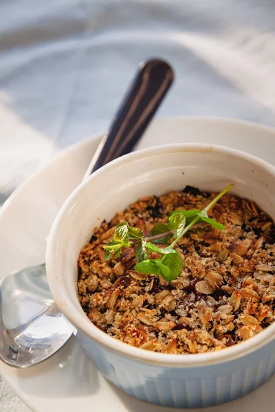 Croccante di avena e mirtillo al forno con menta in un piatto bianco e blu su una tovaglia di lino rustico. Risparmia spazio, vista dall'alto. Il concetto di sana corretta alimentazione per la prima colazione, vegetarianismo . — Foto Stock