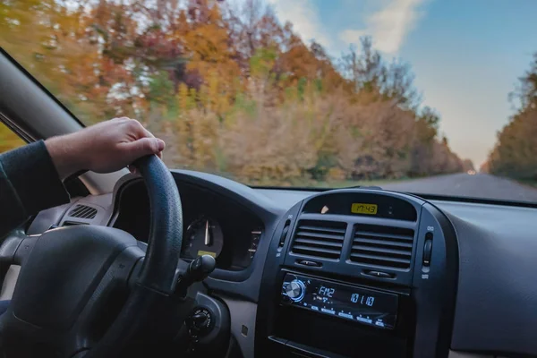 Een man die een auto rijdt op een herfst geel-oranje weg. Close-up van een hand — Stockfoto