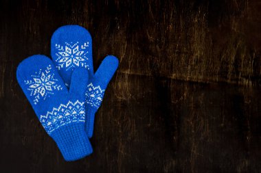 bir çift mavi örgü eldiven koyu mavi-yeşil-kahverengi ahşap üzerinde