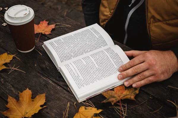 男性女性は秋の公園でコーヒーを飲む本を読んでいます閉じる肩の上に、ぼやけている。トップビュー、スペースを節約。手を見た暗いレトロなスタイルで — ストック写真