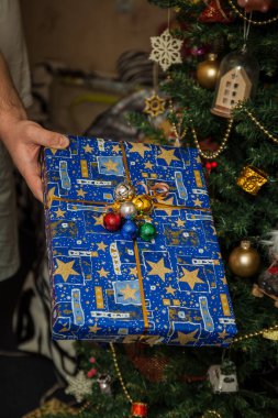 Elinde şenlikli dekore Noel ağacı altında sarılmış hediyeler. Yaşam tarzı