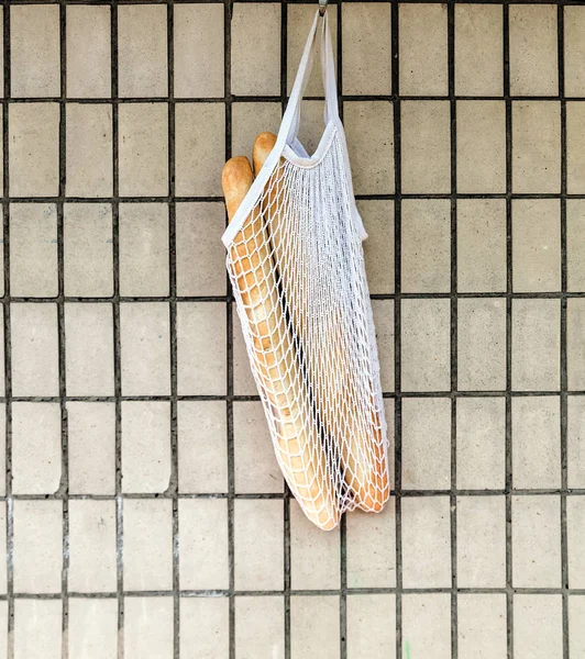 복고풍 벽돌 벽 배경에 매달려 문자열 가방에 신선한 장미 바게트. 맨 위 보기, 복사 공간 — 스톡 사진