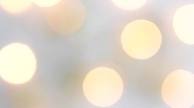 Beyaz arka planda altın bir Noel dekoru ve hareket bulanıklığında ışıklarla yanıp sönen bir çelenk. Yukarıdan bak. Takıntılı. Kavram, Noel ve Yeni Yıl Kutlaması.