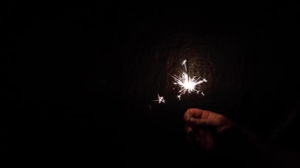 Sparkler płonący iskrami w dłoni na ciemnym tle. Obsesyjnie. Koncepcja, Boże Narodzenie i Nowy Rok. — Wideo stockowe