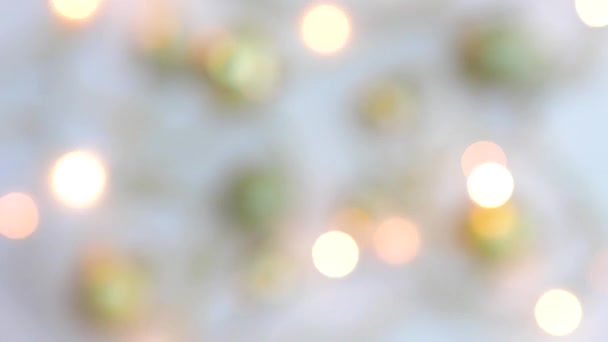 Weihnachtsgoldenes Dekor auf weißem Hintergrund und eine Girlande, die mit Lichtern in Bewegung blinkt, verschwimmen. Blick von oben. Fixiert. Konzept, Weihnachts- und Neujahrsfeier. — Stockvideo