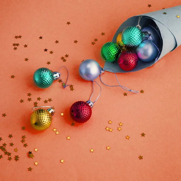 Julhelgen sammansättning, ovanifrån av hantverk kon beströdd med färgglada bollar på en gul-orange bakgrund med kopia utrymme för text. Ett platt ligg. Vinter, vykort mall. — Stockfoto