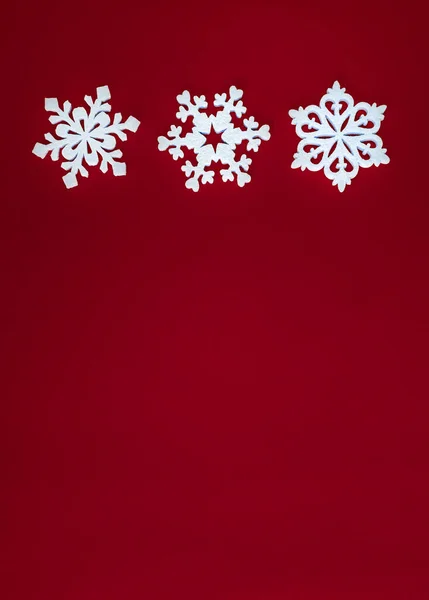 Kerstvakantie compositie, bovenaanzicht witte sneeuwvlokken decoratie op rode achtergrond met kopieerruimte voor tekst. Plat gelegd. Winter, ansichtkaart template — Stockfoto