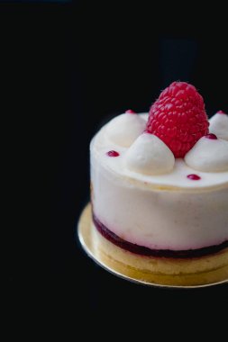 Koyu arkaplanda taze ahududu ile süslenmiş lüks beyaz peynirli kek kreması. Düz yatıyordu. Yakın plan. Boşluğu kopyala.