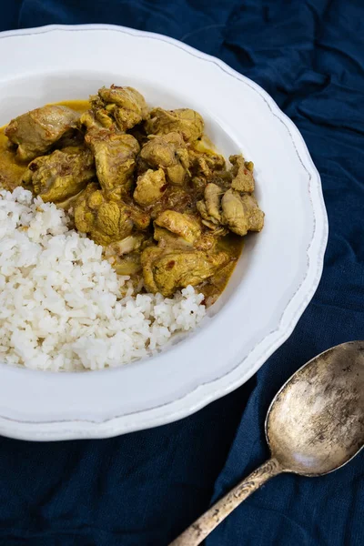 Kari ayam pedas oranye dan nasi basmati putih di piring putih dengan latar belakang biru tua. Masakan tradisional India . — Stok Foto