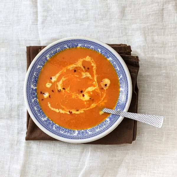Orange pumpkin puree soup with smerana and red chili peppers in a plate with a blue traditional Moroccan pattern on a plain white background. Flat lay. Top view, copy space. — Stock Photo, Image