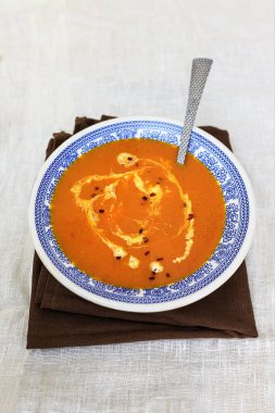 Beyaz arka planda mavi geleneksel Fas desenli bir tabakta smerana ve kırmızı biberli turuncu balkabağı püresi çorbası. Düz yatıyordu. Üst görünüm, alanı kopyala.