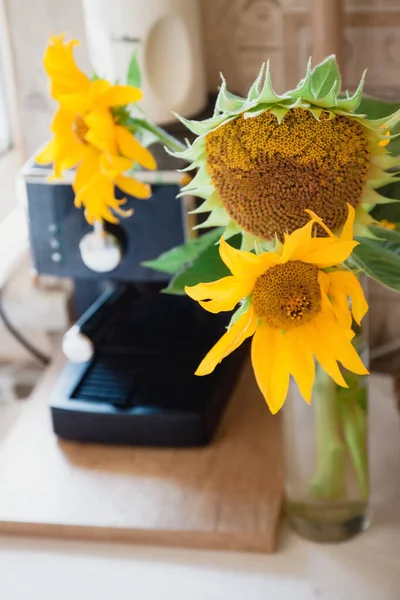 A bouquet with rustic flowers a sunflower stands on a table near the coffee machine