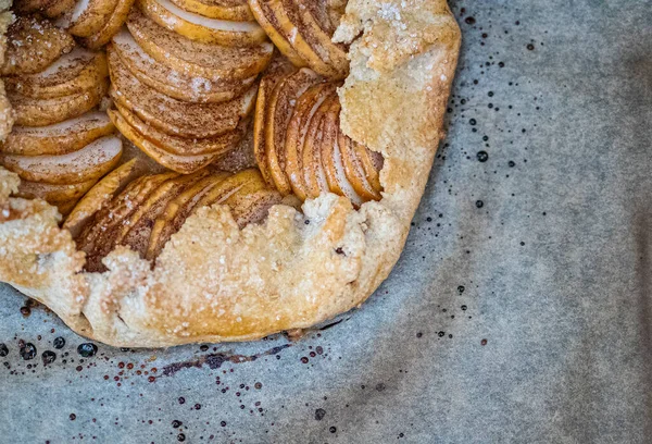 Galette de maçã - torta em assar pergaminho e fundo escuro. Espaço de cópia, flat lay . — Fotografia de Stock