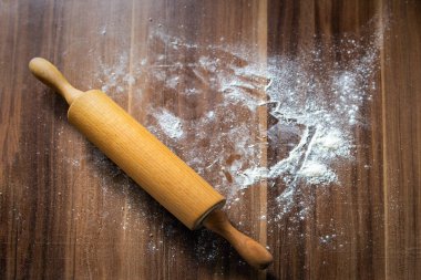 Un kahverengi bir ahşap masa ve merdane üzerine saçılmış. Yukarıdan görüntüle