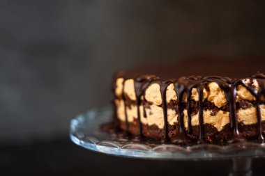 Koyu ahşap zemin üzerinde çikolata damlayan tereyağlı fındık kremalı çikolata katmanları. Minimalizm, uzayı kopyala. Seçici odak, yakın plan.