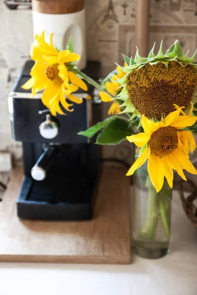 A bouquet with rustic flowers a sunflower stands on a table near the coffee machine