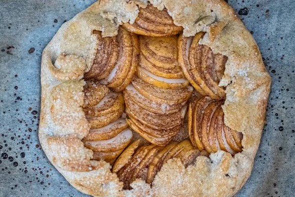 La galette de manzana - la torta sobre el pergamino para hornear y el fondo oscuro. Copiar espacio, plano laico . — Foto de Stock
