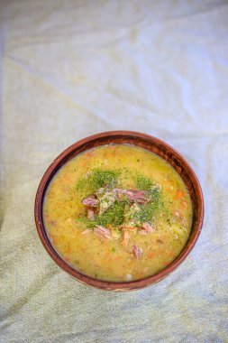 Bezelye çorbası, tütsülenmiş et, kraker ve otlar hafif keten bir masa örtüsünün üzerinde kırsal bir kil tabakta. Minimalizm yaşam tarzı, doğallık. Boşluğu kopyala.