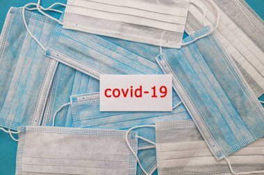 Mavi arka planda, Coronavirus covid 19 yazan tıbbi tek kullanımlık yüz maskeleri. Dünya pandemik koronavirüsü. Salgını durdurun. Sağlık ve gribin önlenmesi ve bulaşıcı