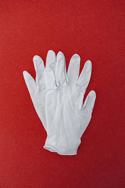 Medical surgical gloves on a red background. World pandemic coronavirus. Health and prevention of influenza and an infectious outbreak. New Coronavirus 2019-nCoV