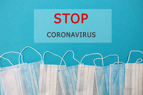 Medyczne jednorazowe maski na niebieskim tle z napisem stop coronavirus covid 19. Światowa pandemia koronawirusa. Powstrzymaj pandemię. Zdrowie i zapobieganie grypie i zakaźnych — Zdjęcie stockowe